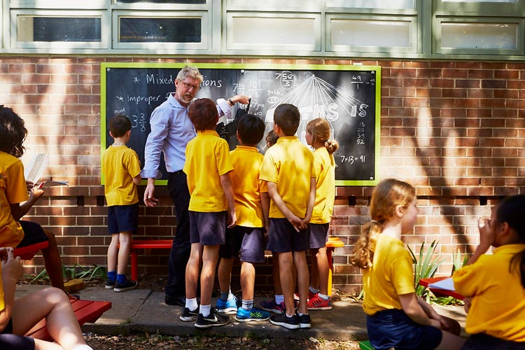 Image of a teacher with students in the outdoor learning area